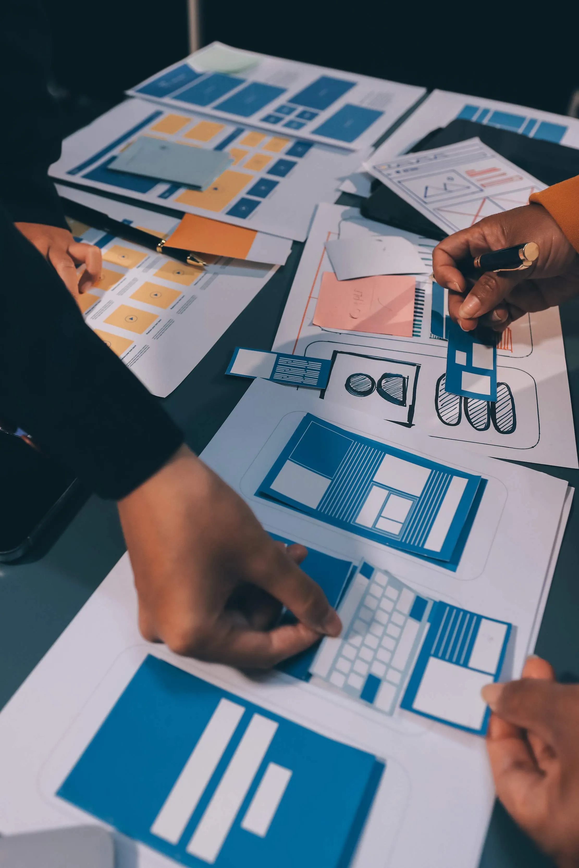 Hands arranging website wireframe sketches during a design discussion
