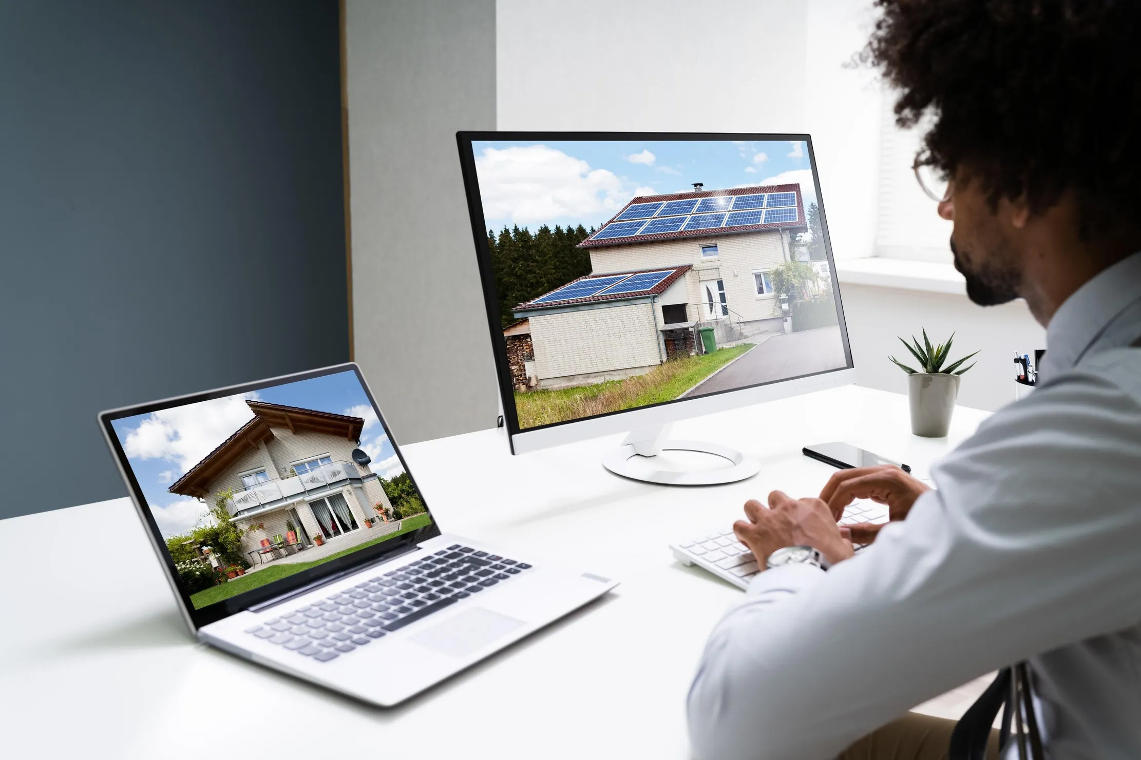 Property manager reviewing real estate listings across a laptop and monitor, representing a lease register review routine
