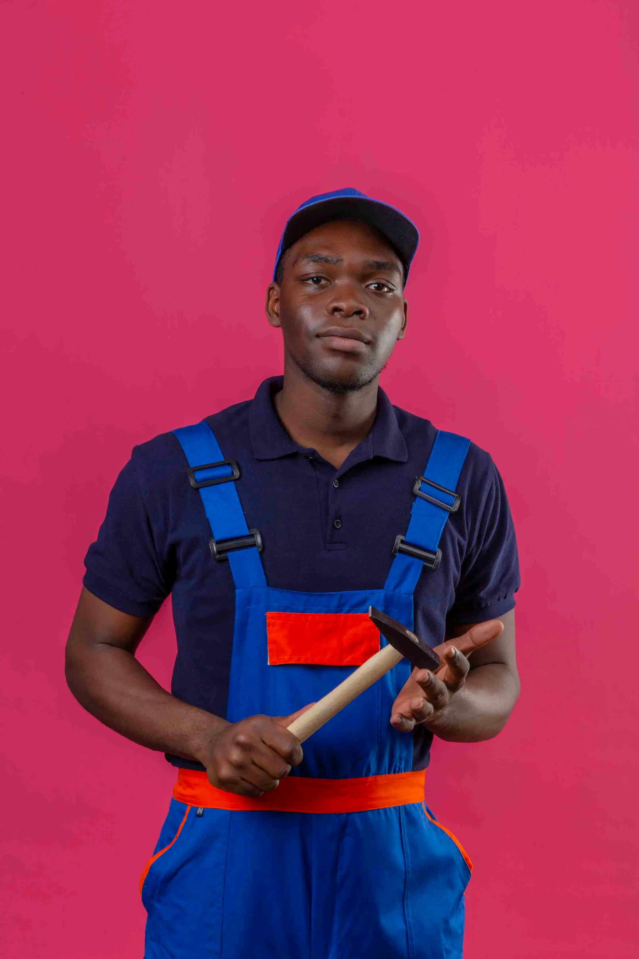 Confident young builder holding a hammer — the skilled professional who prices and packages their own services builds a confidence that transforms how they show up at work